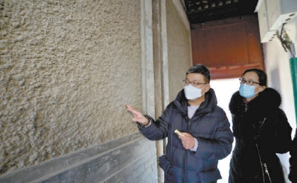 在草厂头条3号院进院门廊，设计师张喆向居民讲解墙上的“堆灰掸浆”工艺。（潘之望 摄）