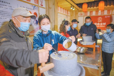 每到周末，赵慧都在北京市腐乳科普馆担任讲解员。她正在引导前来参观的市民体验豆腐制作过程。