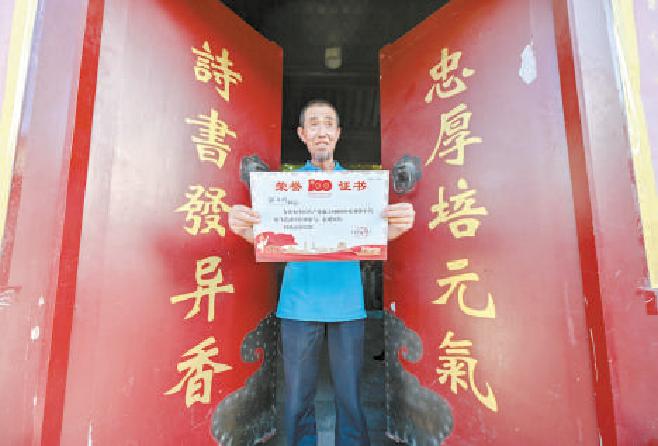 邹立明捧着庆祝中国共产党成立100周年大会和平鸽放飞荣誉证书笑开了怀。
