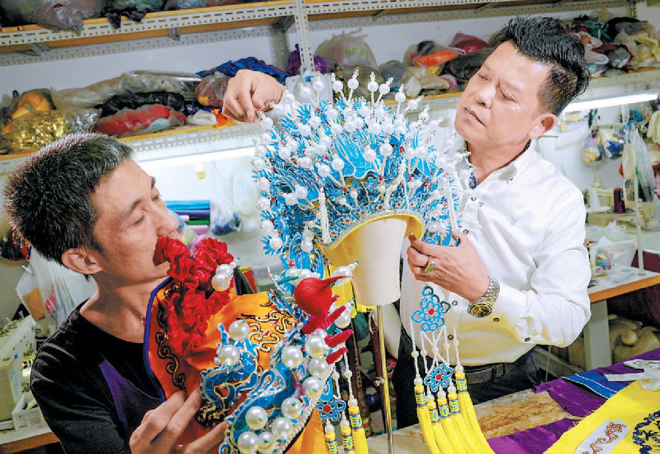 许振海（右）用传统工艺制作的精美戏服、凤冠等。（武亦彬 摄）