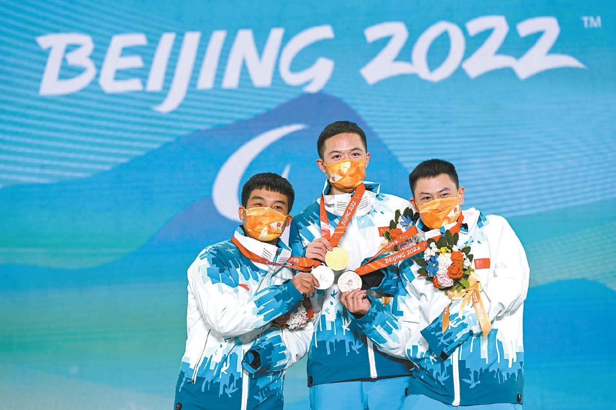 2022年3月7日，中国选手冠军纪立家（中）、亚军王鹏耀（左）和季军朱永钢在北京2022年冬残奥会残奥单板滑雪男子障碍追逐（UL级）比赛奖牌颁发仪式上。（胡超 摄）