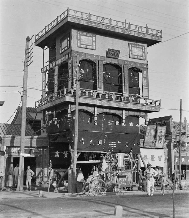 1930年代王府井八面槽某商店，店门前用沙篙起了棚子，商店只有两层高，彩棚可是三层，巨大而招摇，广告效应非同凡响。
