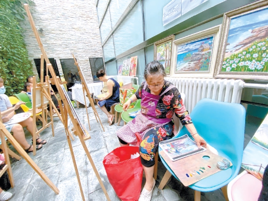 在华业东方玫瑰社区荷锄归养老服务驿站里，居民们正在感受油画魅力。驿站有课程表，居民可以免费参加课程。（陈强 摄）