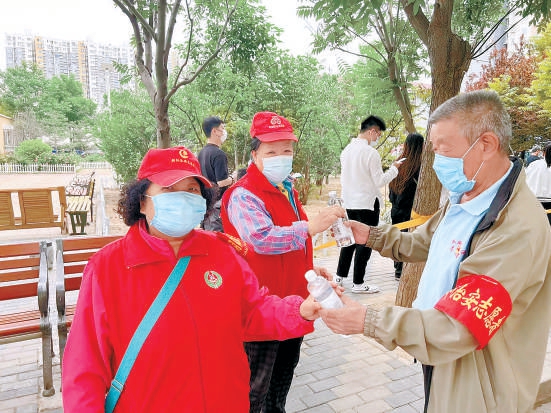 毛景鸾老人（右）给志愿者送水。（赵语涵 摄）