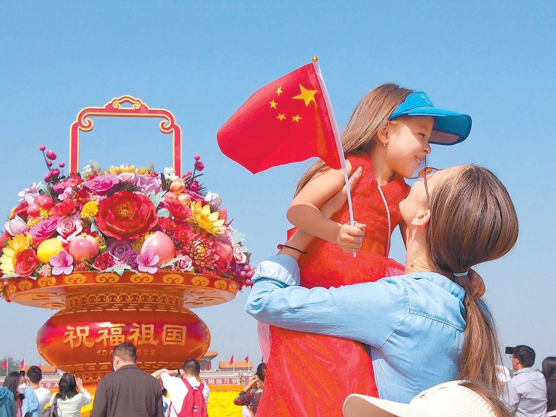 天安门广场上，一对母女在“祝福祖国”巨型花果篮前拍照留影。