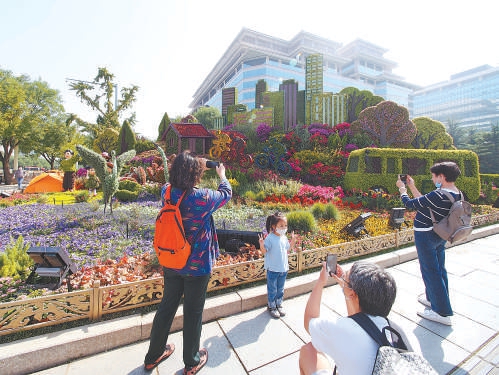 在西单东南角“绿色生活”花坛前，市民拍照留影。