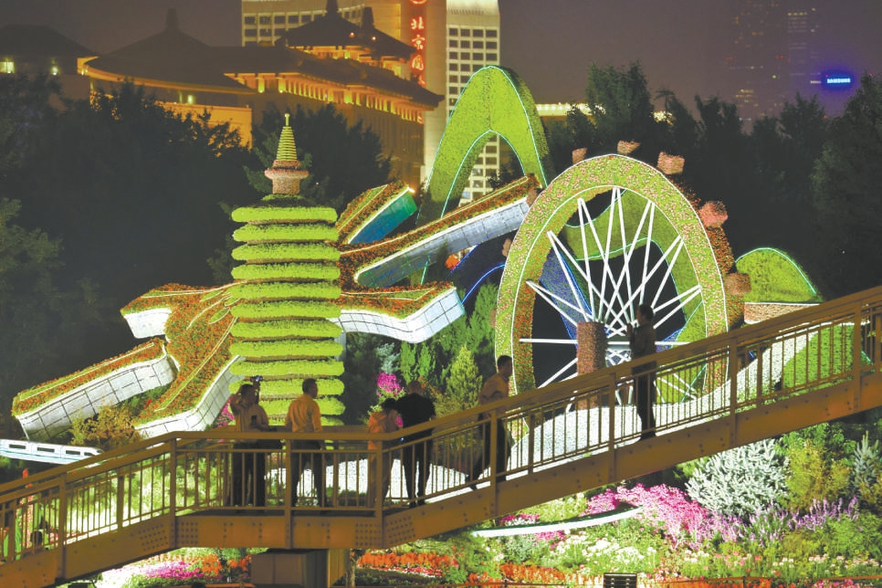 9月28日晚，在东单路口南侧人行天桥，很多市民驻足观赏“协调发展”花坛。