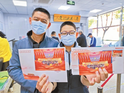 成功购买到纪念邮票，一对邮迷父子兴奋地展示。