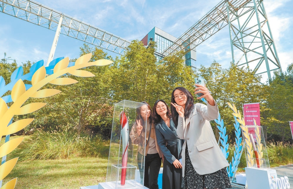 图为在冬奥精神主题展上，游客和冬奥会火炬合影。