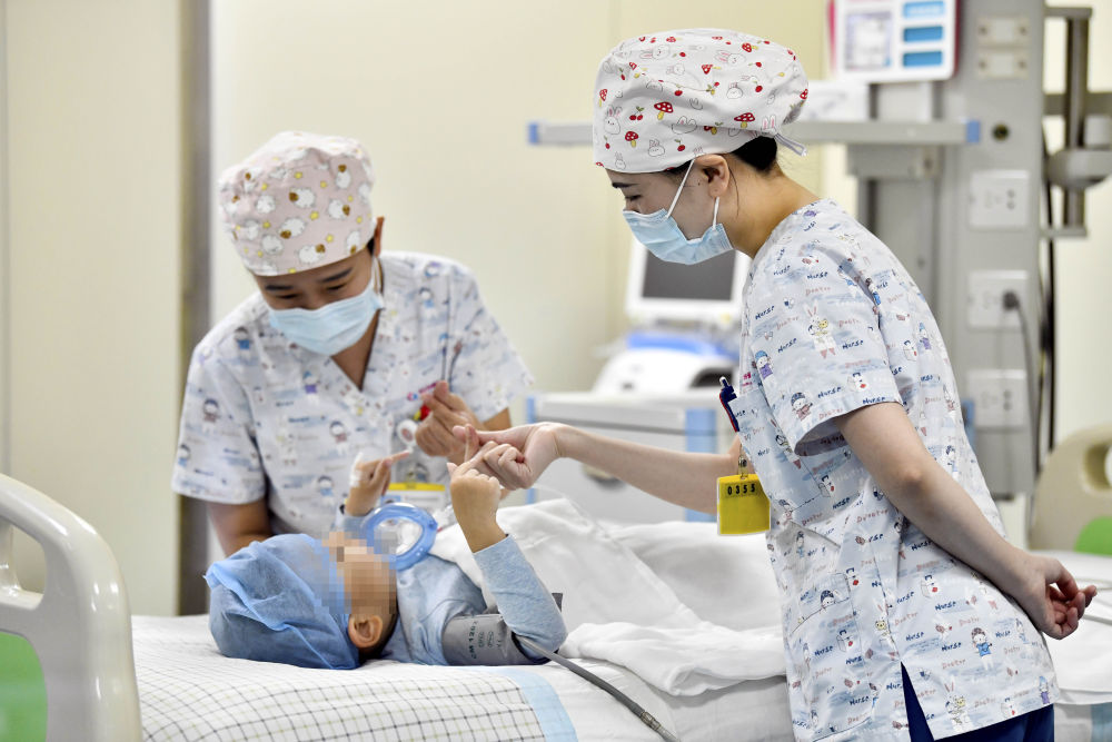 在山东省枣庄市妇幼保健院儿童ICU病房，医护人员为完成靶向治疗药物诺西那生钠的4岁脊髓性肌萎缩症患儿加油鼓劲（2022年1月1日摄）。诺西那生钠注射液是我国首个获批治疗脊髓性肌萎缩症的进口药物，2019年进入中国市场时，每针价格近70万元。在2021年国家医保目录药品谈判中，以3.3万元每针的价格进入新版医保药品目录。