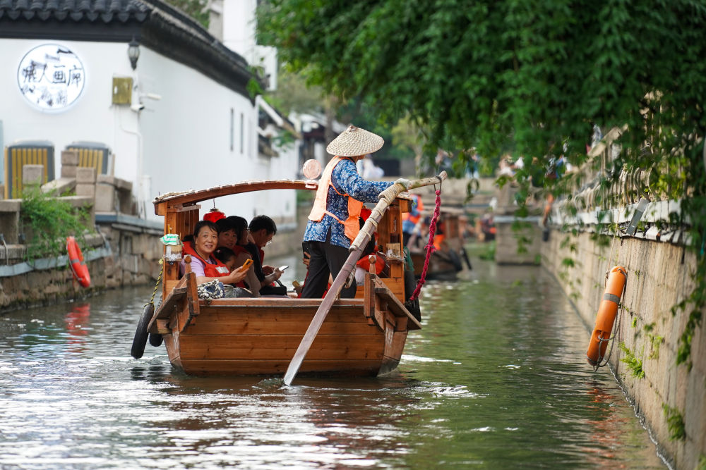 游客乘船在苏州平江历史文化街区休闲游玩（2023年7月3日摄）。