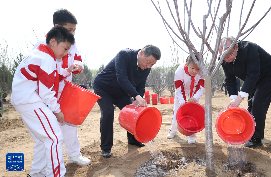 4月3日，党和国家领导人习近平、李强、赵乐际、王沪宁、蔡奇、丁薛祥、李希、韩正等来到北京市通州区潞城镇参加首都义务植树活动。这是习近平同少先队员一起给刚栽下的树苗浇水。