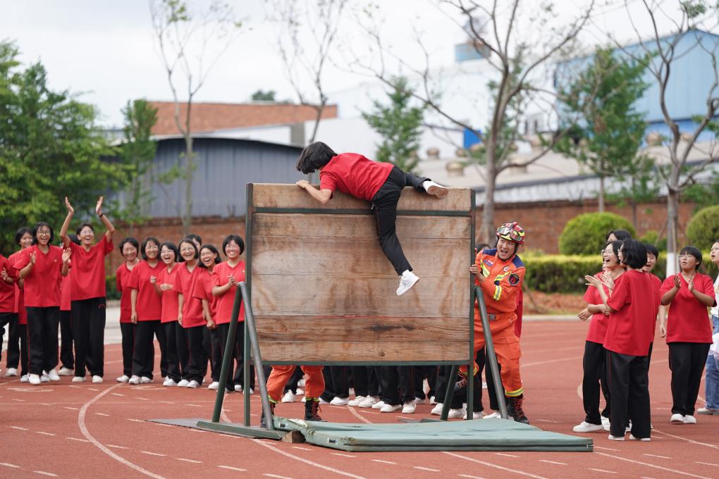 云南丽江华坪女子高级中学学生在体验翻越障碍板。