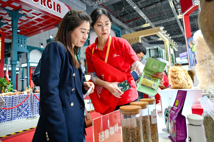 11月7日，一名观众（左一）在第七届进博会国家展秘鲁馆了解秘鲁咖啡。