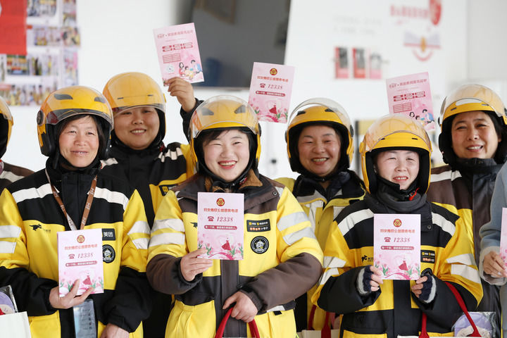 2025年3月7日，在山东省临沂市郯城县郯城街道龙泉社区，外卖女骑手展示妇联发放的妇女维权公益服务知识手册。