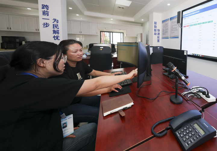 2025年5月12日，在上海市杨浦区殷行街道第五综合网格工作站，工作人员讨论通过“一键呼叫”与居民沟通。