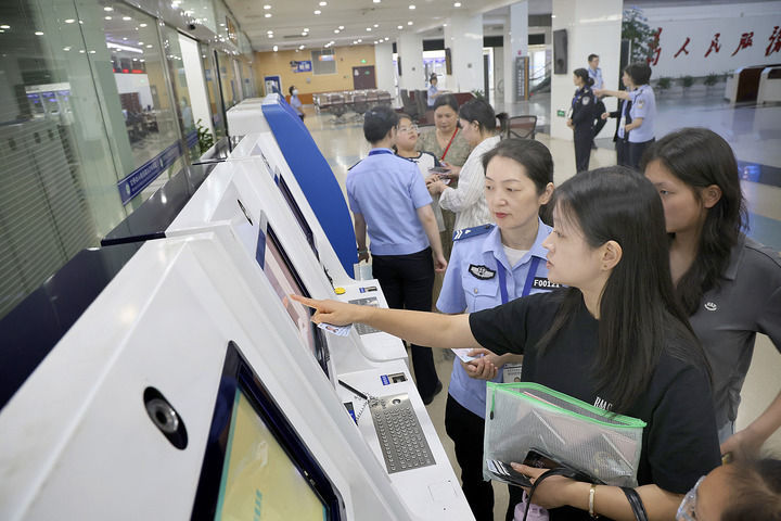 2025年6月25日，工作人员在江苏南通市政务中心出入境办证大厅指导市民使用自助填表系统。
