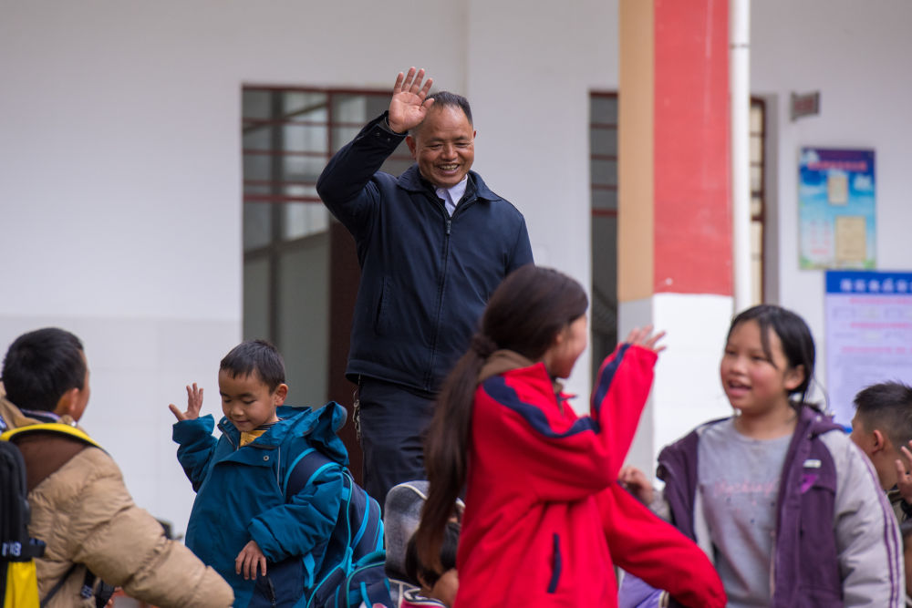 2025年2月18日，在落松地小学，农加贵（中）下课后和学生挥手告别。