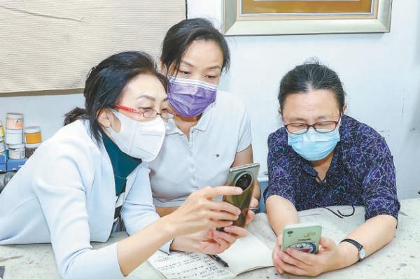 北京开放大学教师向社区老人讲解智能手机用法。