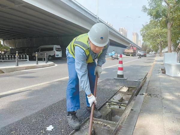 北京排水集团工作人员对雨水口进行清掏，保障安全度汛。