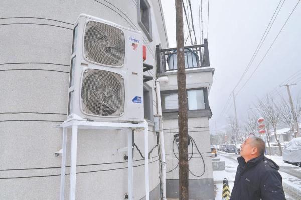 门头沟区丁家滩村党支部书记艾有成在村内巡查，村民新更换的空气源热泵让他安心不少。