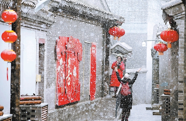 雪中京城美景如画，游客在草厂四条胡同游玩拍照。