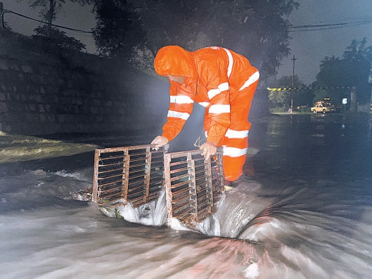 公路养护人员徒手清掏雨水箅子。