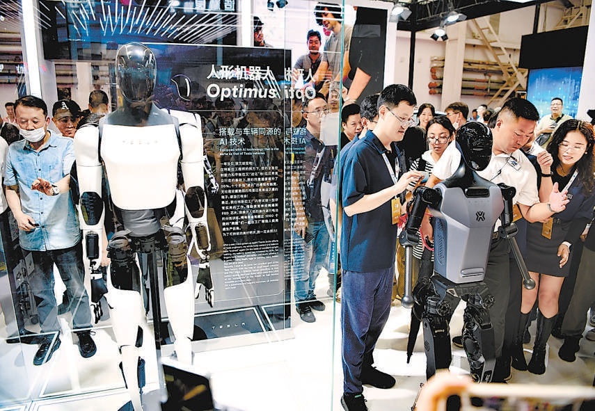 “天工”（右）和特斯拉Optimus（左）两位明星人形机器人同框，被粉丝团团围住。
