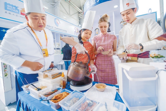 公共开放日，三名留学生正在教育服务展区学习制作老北京面茶。