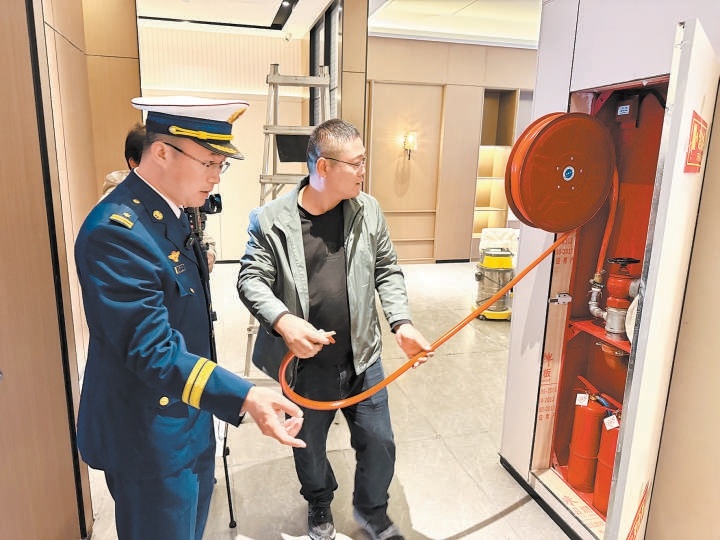 张世青（左）检查酒店工作人员对消防技能的掌握情况。