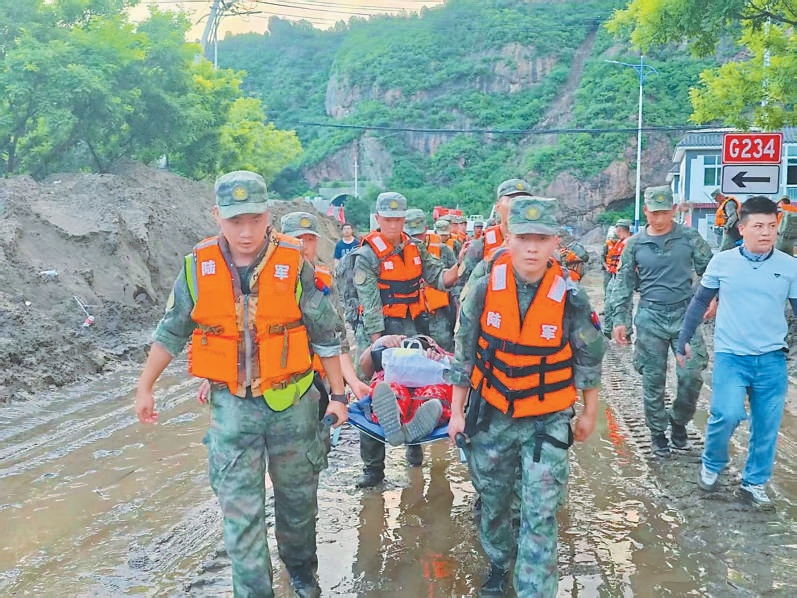 北京卫戍区官兵转移一位行动不便的被困群众。