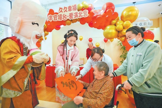 工作人员为老人送上寓意美好的书法作品。( 工作人员为老人送上寓意美好的书法作品。(