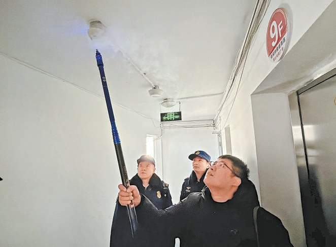 工作人员现场测试楼道新安装的烟感报警器。