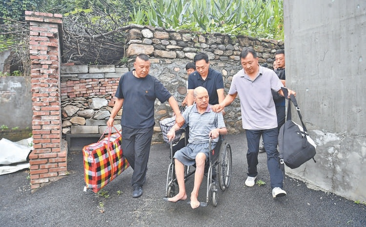 密云区石城镇捧河岩村，75岁的瘫痪老人谭凤林，在村干部的帮助下进行转移。