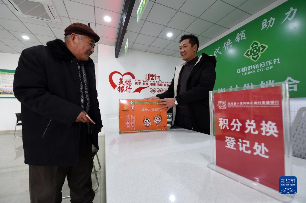 在安徽省滁州市凤阳县小岗村，村民缪守鲁（左）在村里“美德银行”用积分兑换生活物品（2021年1月30日摄）。（周牧 摄）
