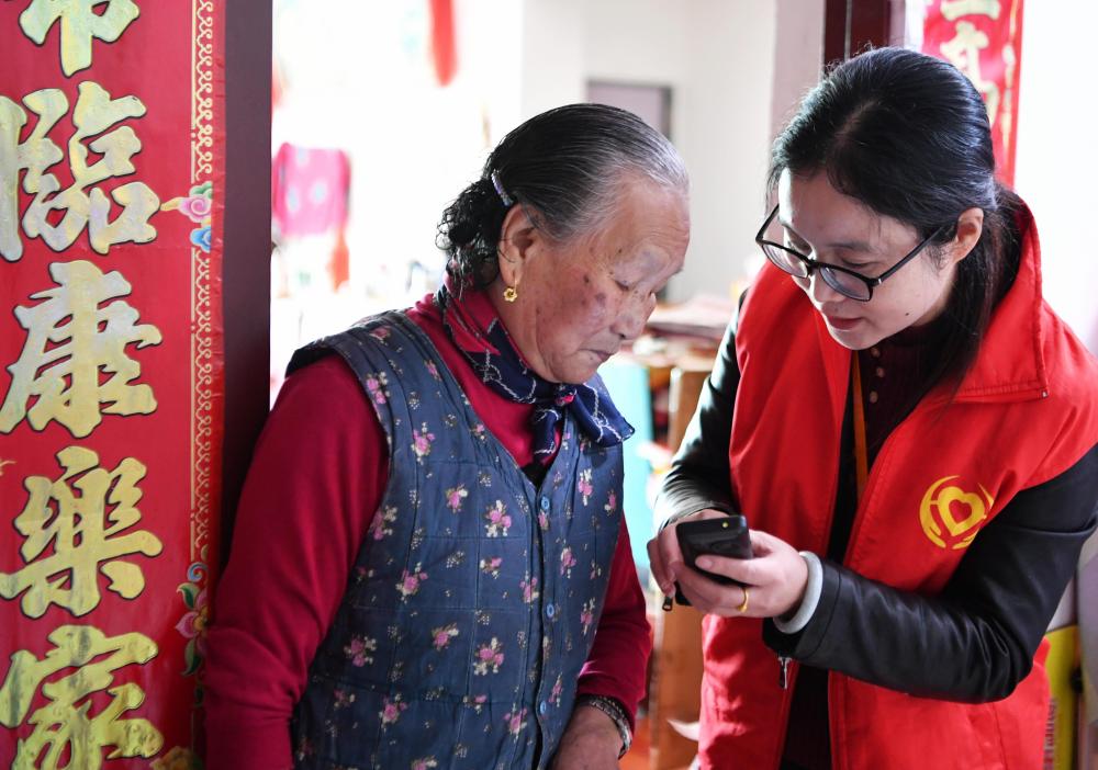 在福州市长乐区航城街道筹岐村，智慧养老平台派驻社区的助老员（右）在为老人陈凤英（左）讲解养老定制手机的用法（2021年11月26日摄）。