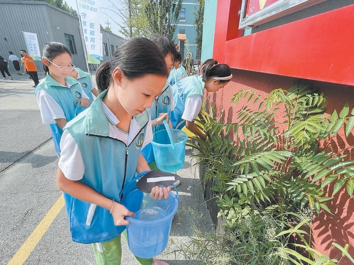梨园学校学生参与绿地大扫除。