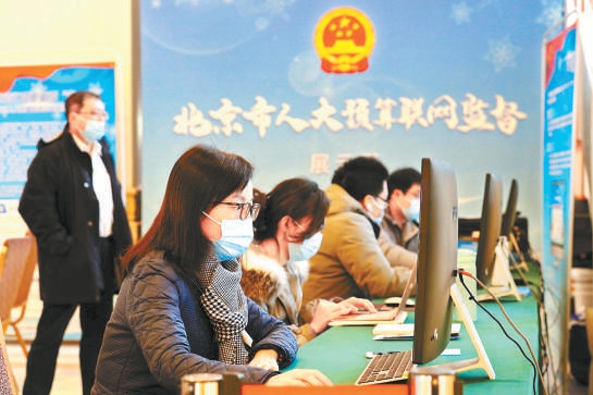 市人代会上，人大代表们在利用预算联网监督系统查询政府计划预算报告等重要信息。