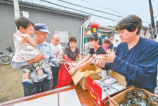 8月14日，在密云区墙子路村，村民自发参与灾后物资发放工作。