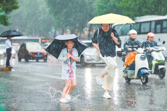 6月14日，在丰台区蒲方路，市民在雨中享受清凉。