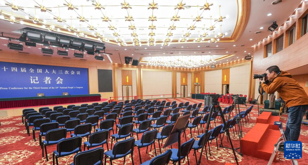 2月27日，一名记者在全国两会新闻中心新闻发布厅拍摄。