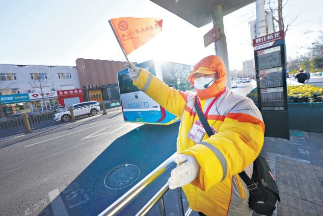 在通州区耿庄桥北公交站台，公共文明引导员在寒风中坚守岗位，引导车辆进出站台和乘客有序上下车。