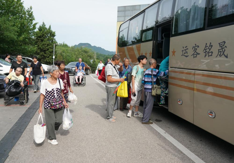 8月5日，北京市房山区青龙湖镇口头村村民在安置点登上接他们回家的大巴。