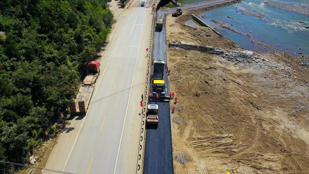 8月20日，在房山区涞宝路，施工队在为抢修出的临时便道路面铺设沥青。（房山公路分局供图）