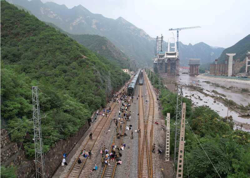 8月2日，受困列车旅客在救援人员帮助下徒步赶往转运客车（无人机照片）。