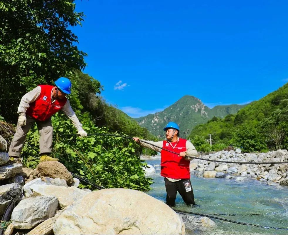 房山区张坊镇，国网北京电力海淀电力保通抢修队在河两岸开展电杆架设工作。