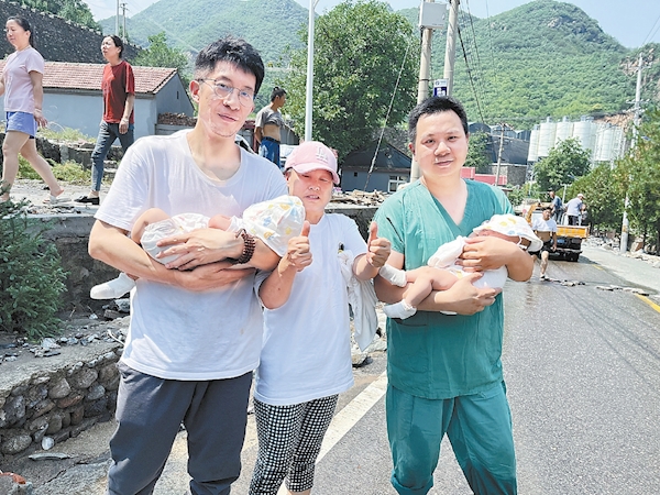 汤鑫（右）和胡浩抱着救援出来的双胞胎男婴向安全地区转移。