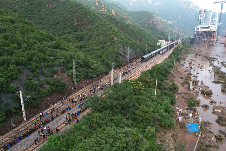 8月2日，受困列车旅客在救援人员帮助下徒步赶往转运客车（无人机照片）。