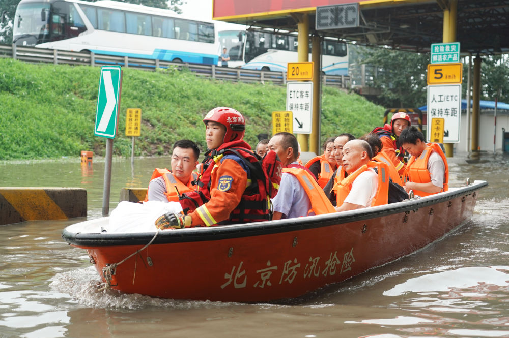 8月2日，在北京市房山区的京港澳高速琉璃河出口，受灾群众乘坐冲锋舟前往转运车辆乘车点。