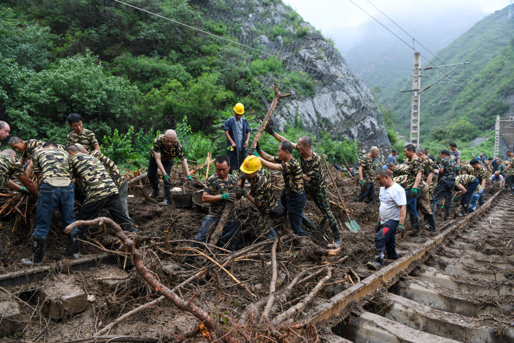 8月1日，在北京市门头沟区水峪嘴村附近一段被阻断的铁路线上，中铁六局工作人员在清理轨道上的杂物，全力恢复交通。